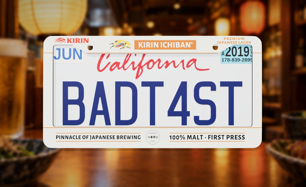 Kirin Ichiban license plate frame in white with the Kirin logo and Kirin Ichiban label, front view on a lantern-lit izakaya counter background