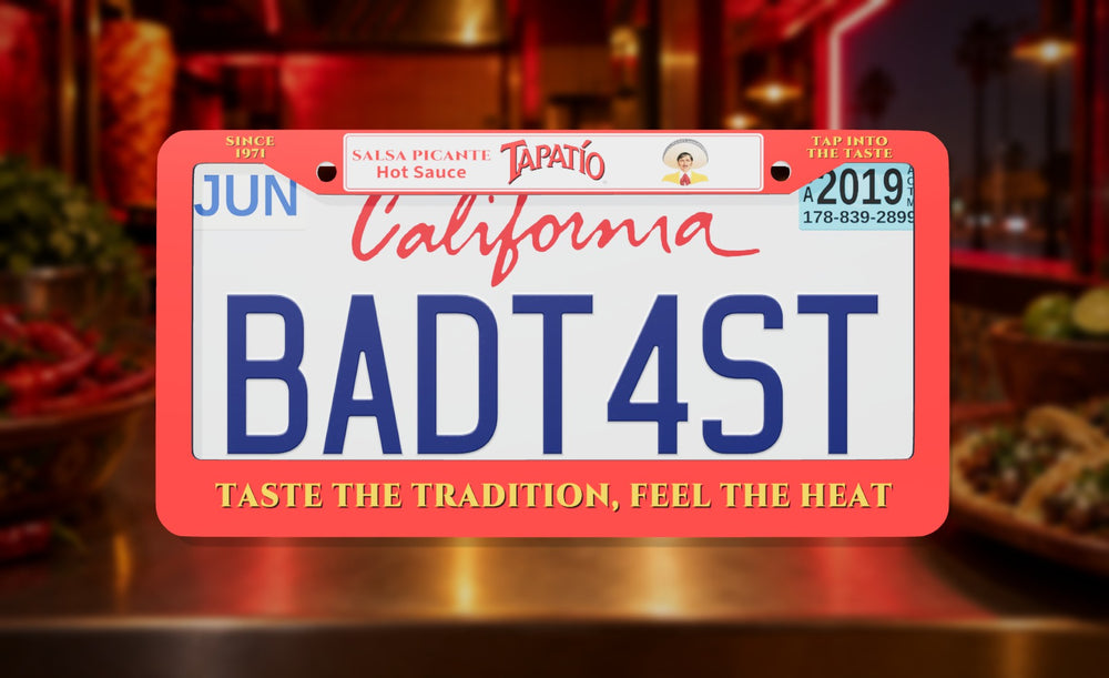 Tapatío license plate frame in red with the Tapatío logo and Taste the Tradition, Feel the Heat, front view on a taqueria counter at night background