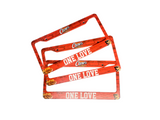 Red license plate holder with 'One Love' and 'Cubs' branding on a gray surface