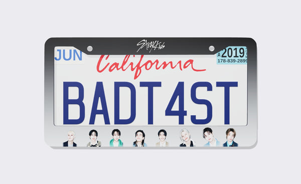 Stray Kids license plate frame front view: charcoal-to-silver gradient frame with the white Stray Kids script logo on top and eight member portraits along the bottom, shown on a California plate